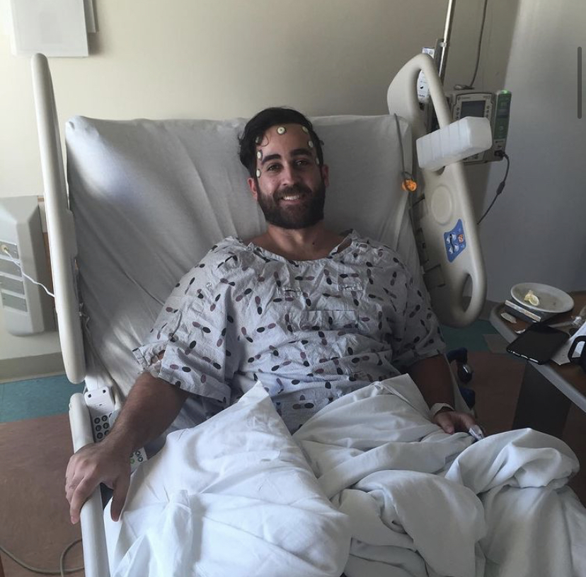 Alex smiling from his hospital bed following brain surgery in 2016